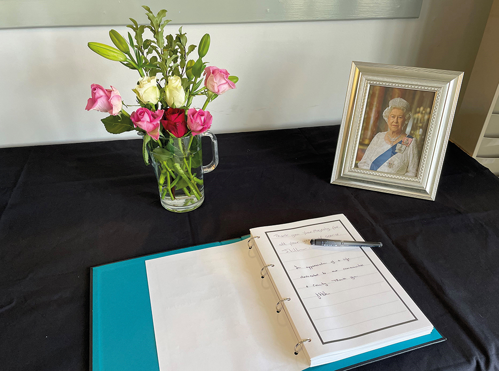 book of condolence, flowers and photo of the Queen