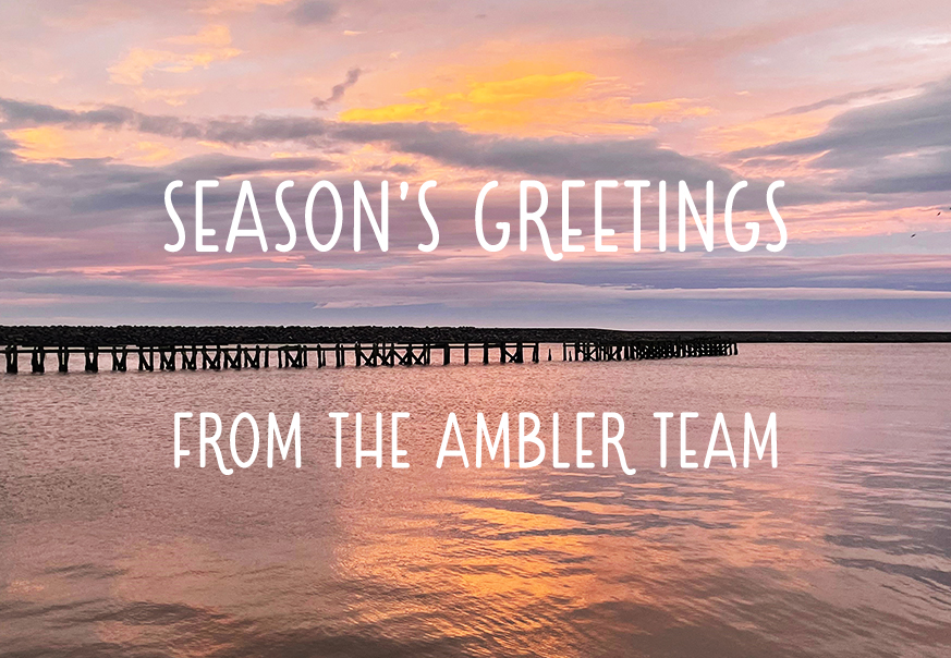 Sunset over Amble Harbour with the words Season's Greetings from The Ambler Team